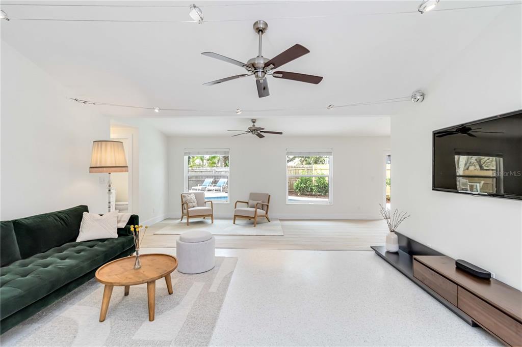 A bright living room features a green velvet sofa, two armchairs, and a ceiling fan — 5107 SAINT ALBANS AVENUE, SARASOTA, FL