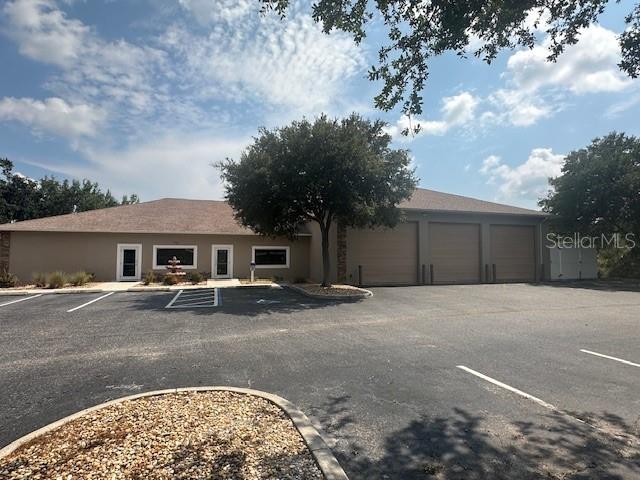 A tan commercial building features three garage doors, two entry doors, and a paved parking lot — 718 60TH STREET COURT E, BRADENTON, FL