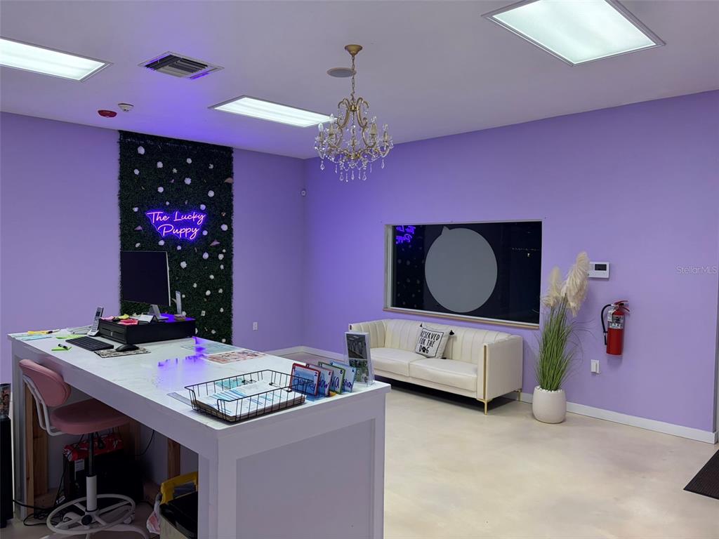 A reception area features a white desk, purple walls, a crystal chandelier, and a white sofa — 718 60TH STREET COURT E, BRADENTON, FL