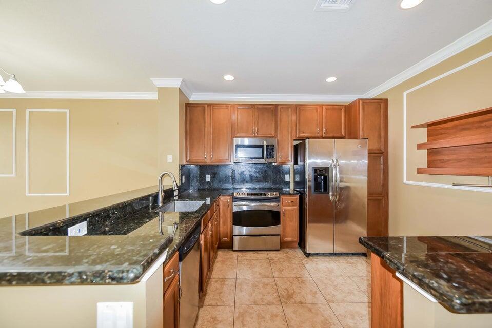 A kitchen with wood cabinets, stainless steel appliances, and dark granite countertops — 9687 Lago Drive, Boynton Beach FL 33472, BOYNTON BEACH, FL