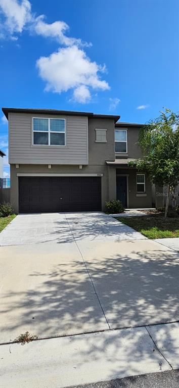 A two-story house with a dark brown garage door and light brown exterior siding — 9910 SPANISH LIME COURT, RIVERVIEW, FL