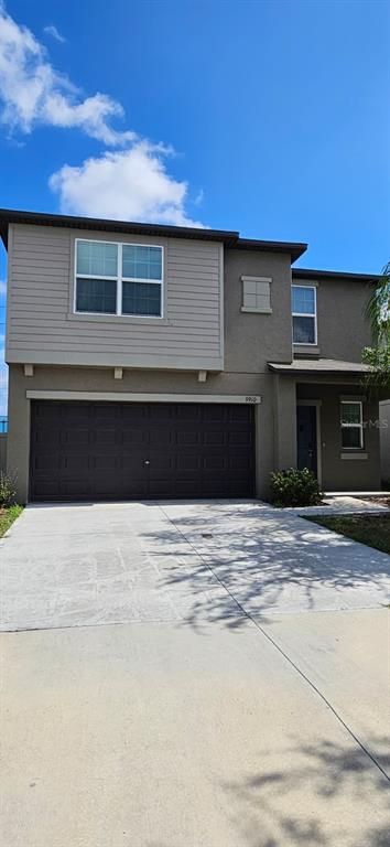 A two-story house with a gray stucco exterior, a two-car garage, and a concrete driveway — 9910 SPANISH LIME COURT, RIVERVIEW, FL