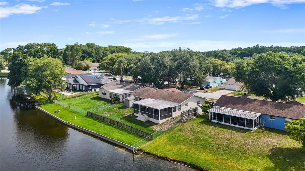 An aerial view shows several waterfront houses with screened-in porches and fenced backyards — 4341 OTTER WAY, NEW PORT RICHEY, FL