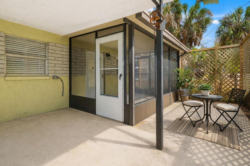 A concrete patio features a screened-in porch, a small bistro table, and lattice fencing — 4489 FISHMAN AVENUE, WEEKI WACHEE, FL