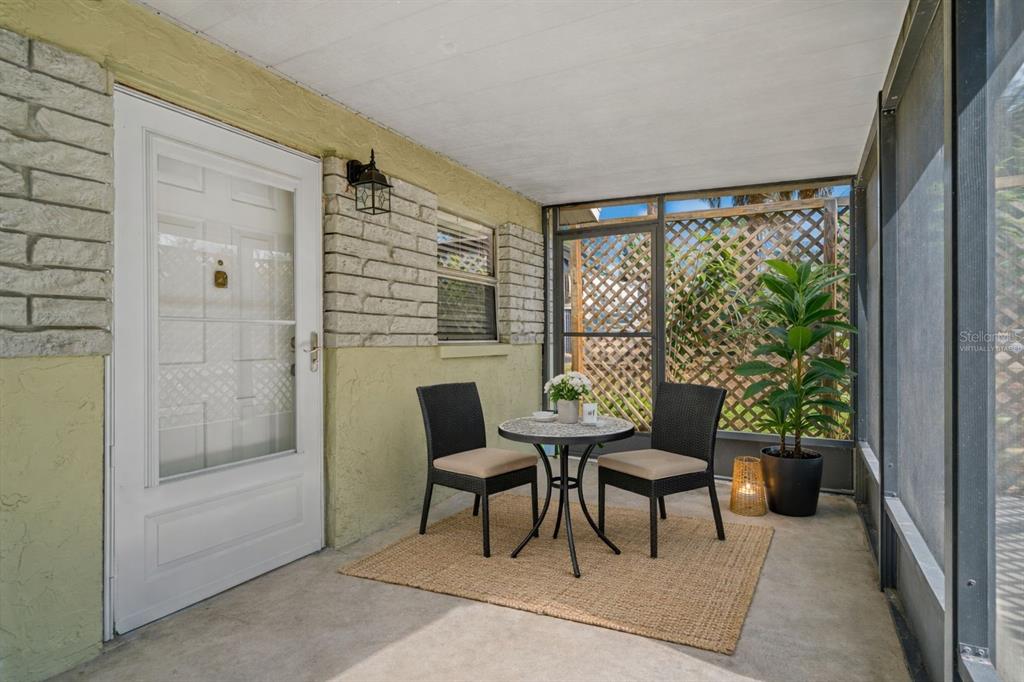 A screened-in porch features a small bistro table with two chairs on a woven rug — 4489 FISHMAN AVENUE, WEEKI WACHEE, FL