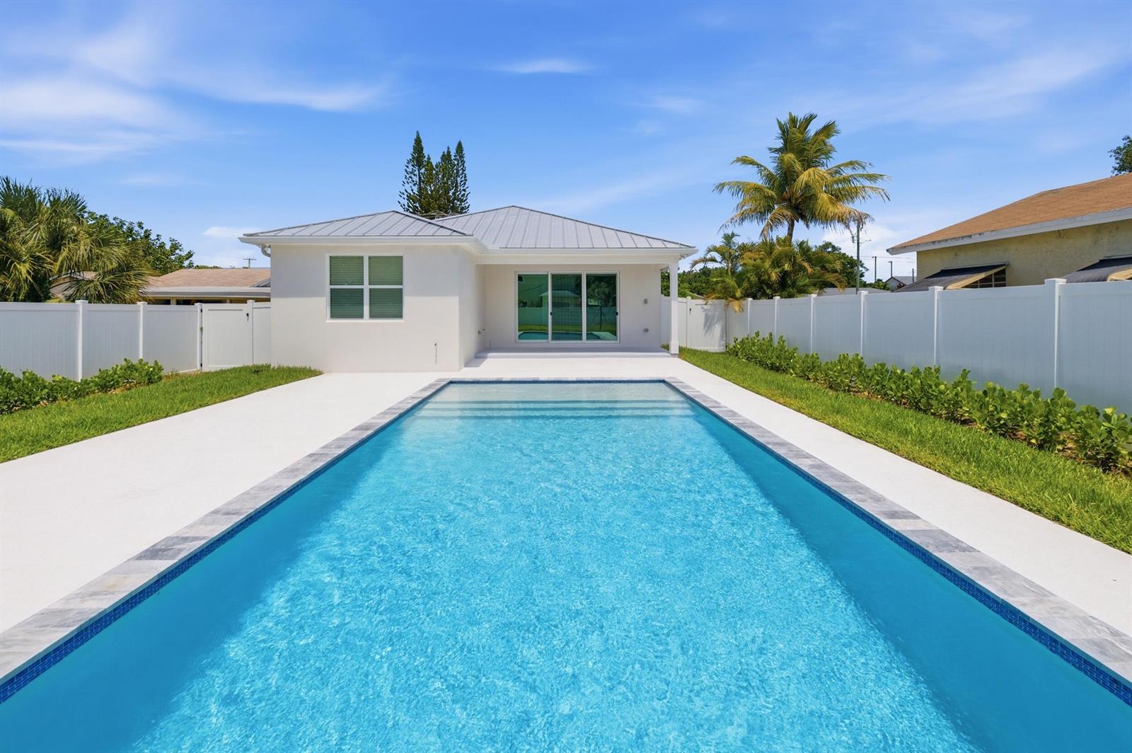 A white house with a metal roof features a long rectangular swimming pool in back — 316 SW 4th Avenue, Delray Beach FL 33444, DELRAY BEACH, FL
