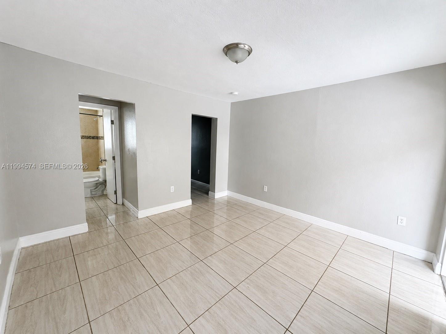 An empty room features light gray walls, beige tile flooring, and two doorways — 1920 Washington Ave # 3, Opa-Locka FL 33054, OPA-LOCKA, FL
