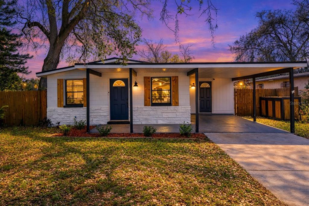 A single-story house with a white brick facade, blue front door, and an attached carport — 3007 CHIPCO STREET, TAMPA, FL