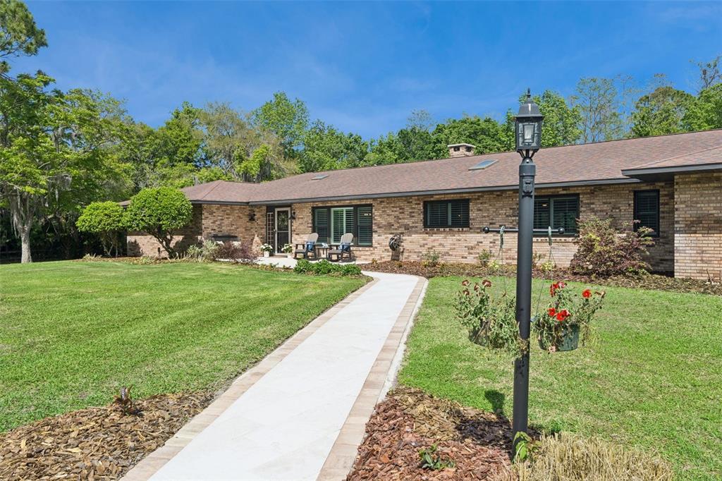 A brick ranch-style house features a paved walkway leading to the front entrance — 1908 POPPY LANE, PORT ORANGE, FL