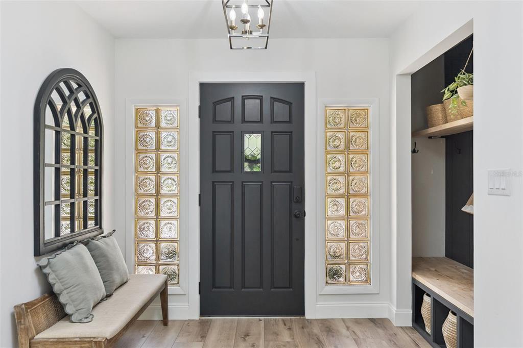 An entryway features a dark front door flanked by glass block windows and a bench — 1908 POPPY LANE, PORT ORANGE, FL