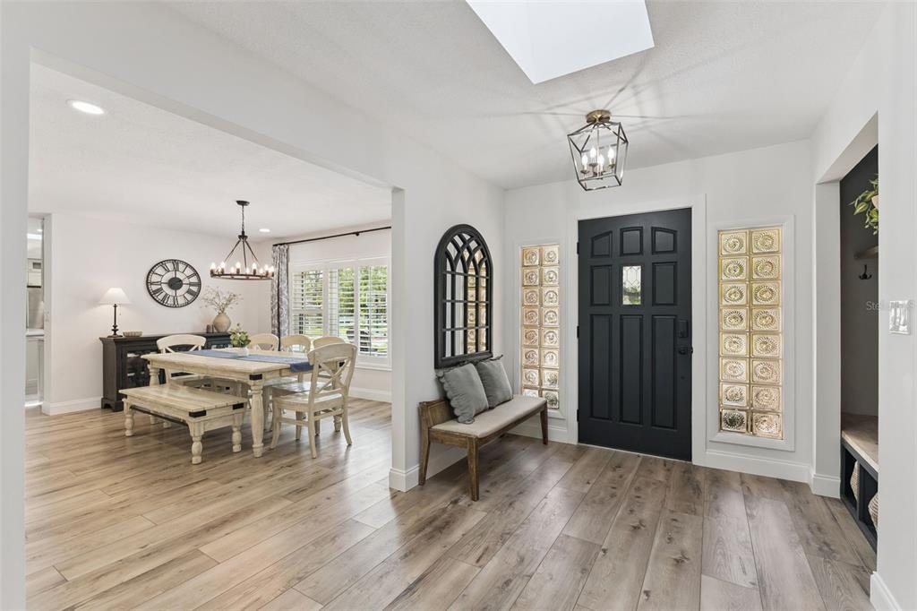 An entryway with wood-look flooring, a black front door, and glass block side windows — 1908 POPPY LANE, PORT ORANGE, FL