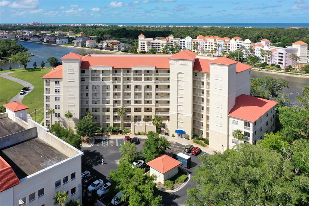 An aerial view shows a multi-story apartment building with a red roof near water — 146 PALM COAST RESORT BOULEVARD UNIT 704, PALM COAST, FL
