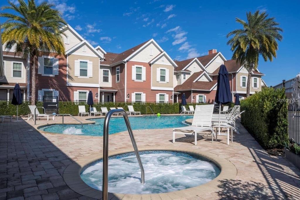 A swimming pool and hot tub are situated in front of a multi-story residential building — 7514 SUNVILLE AVENUE, KISSIMMEE, FL