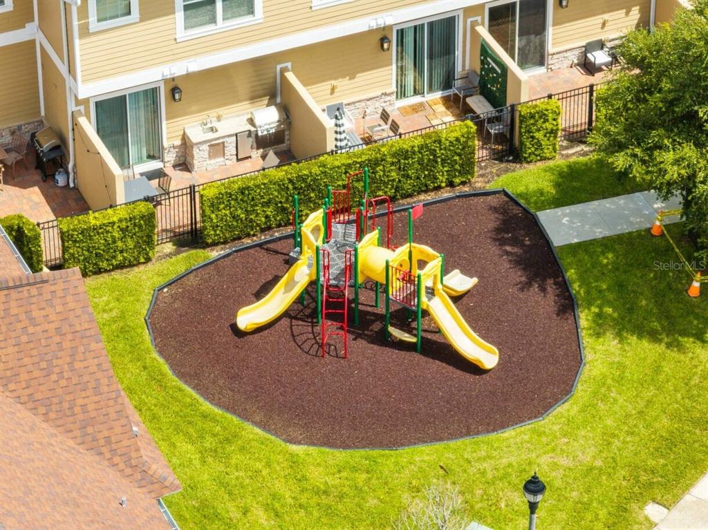 An aerial view shows a playground with yellow slides situated next to a residential building — 7514 SUNVILLE AVENUE, KISSIMMEE, FL