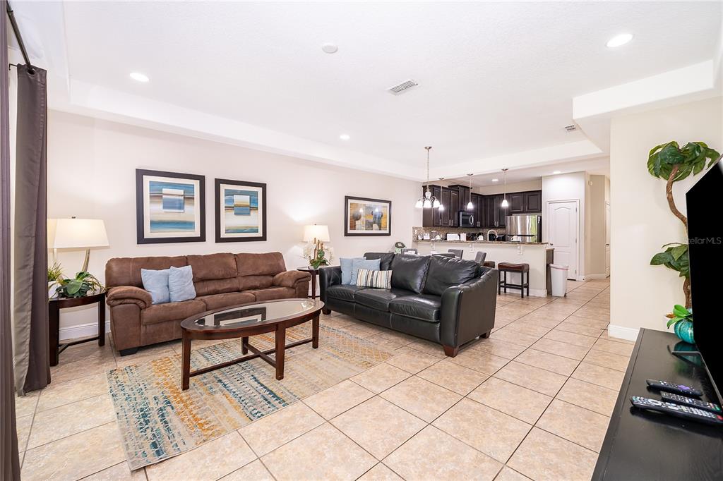A living room with tile floors, two sofas, and an open kitchen in the background — 8213 ROSEVILLE BOULEVARD, DAVENPORT, FL