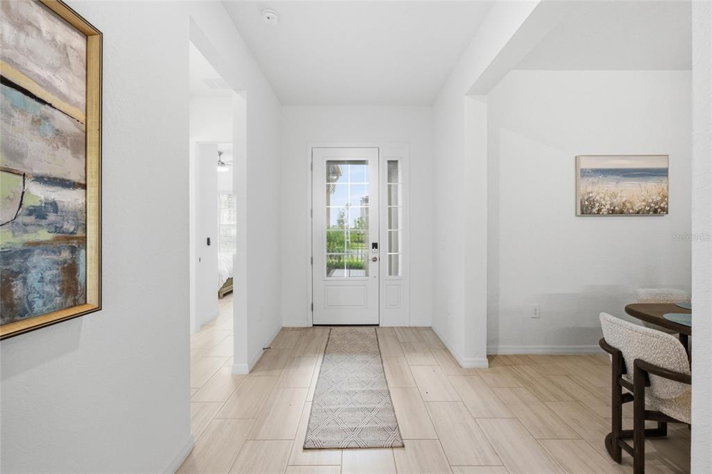 A bright entryway features white walls, light wood-look tile flooring, and a glass-paneled front door — 19047 SCALLOP LOOP, LAKEWOOD RANCH, FL
