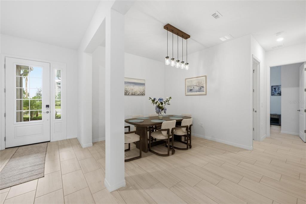 A dining area with a wooden table, chairs, and a linear pendant light fixture — 19047 SCALLOP LOOP, LAKEWOOD RANCH, FL