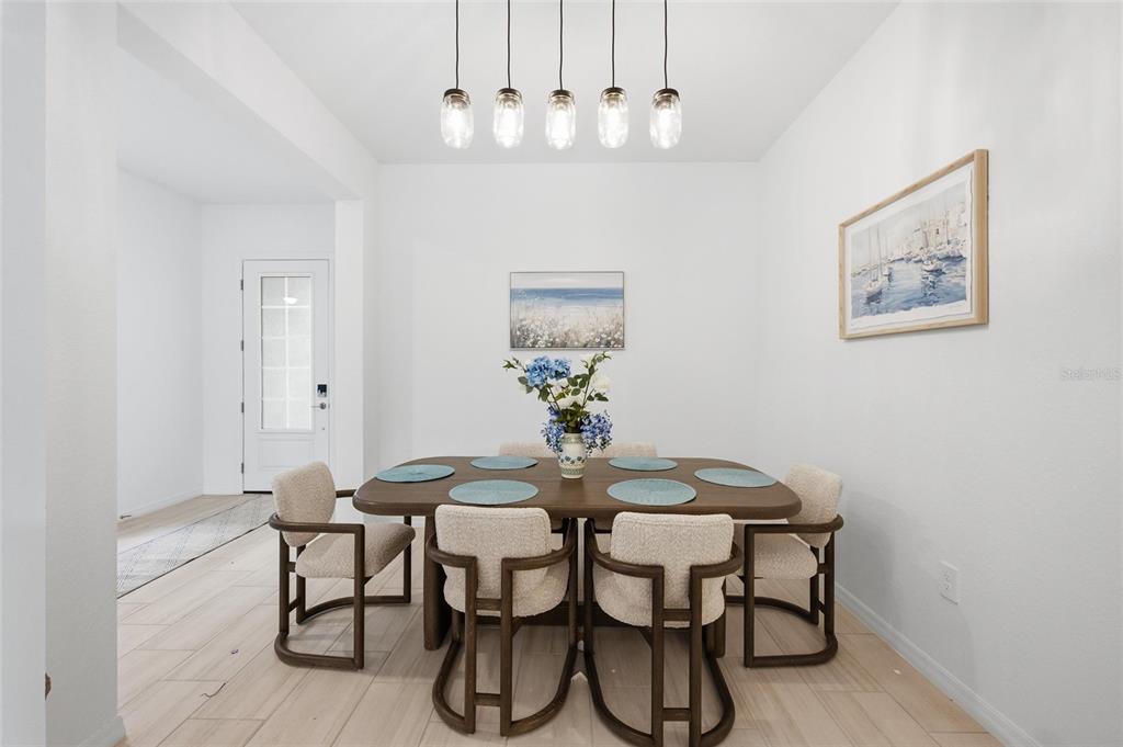 A dining room features a wooden table with six chairs under a five-light pendant fixture — 19047 SCALLOP LOOP, LAKEWOOD RANCH, FL