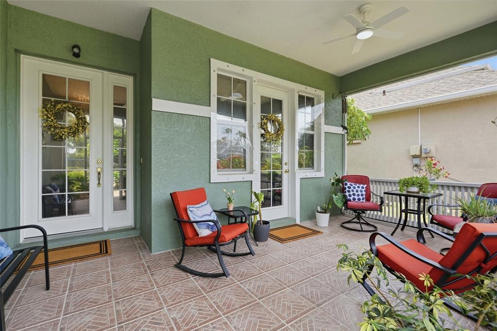 A covered patio features green stucco walls, tiled flooring, outdoor furniture, and two glass doors — 1509 SCARLETT AVENUE, NORTH PORT, FL