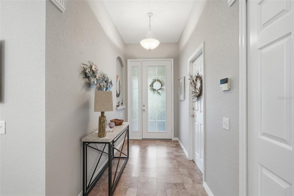 A bright entryway features a glass-paneled front door, tile flooring, and a console table — 1509 SCARLETT AVENUE, NORTH PORT, FL