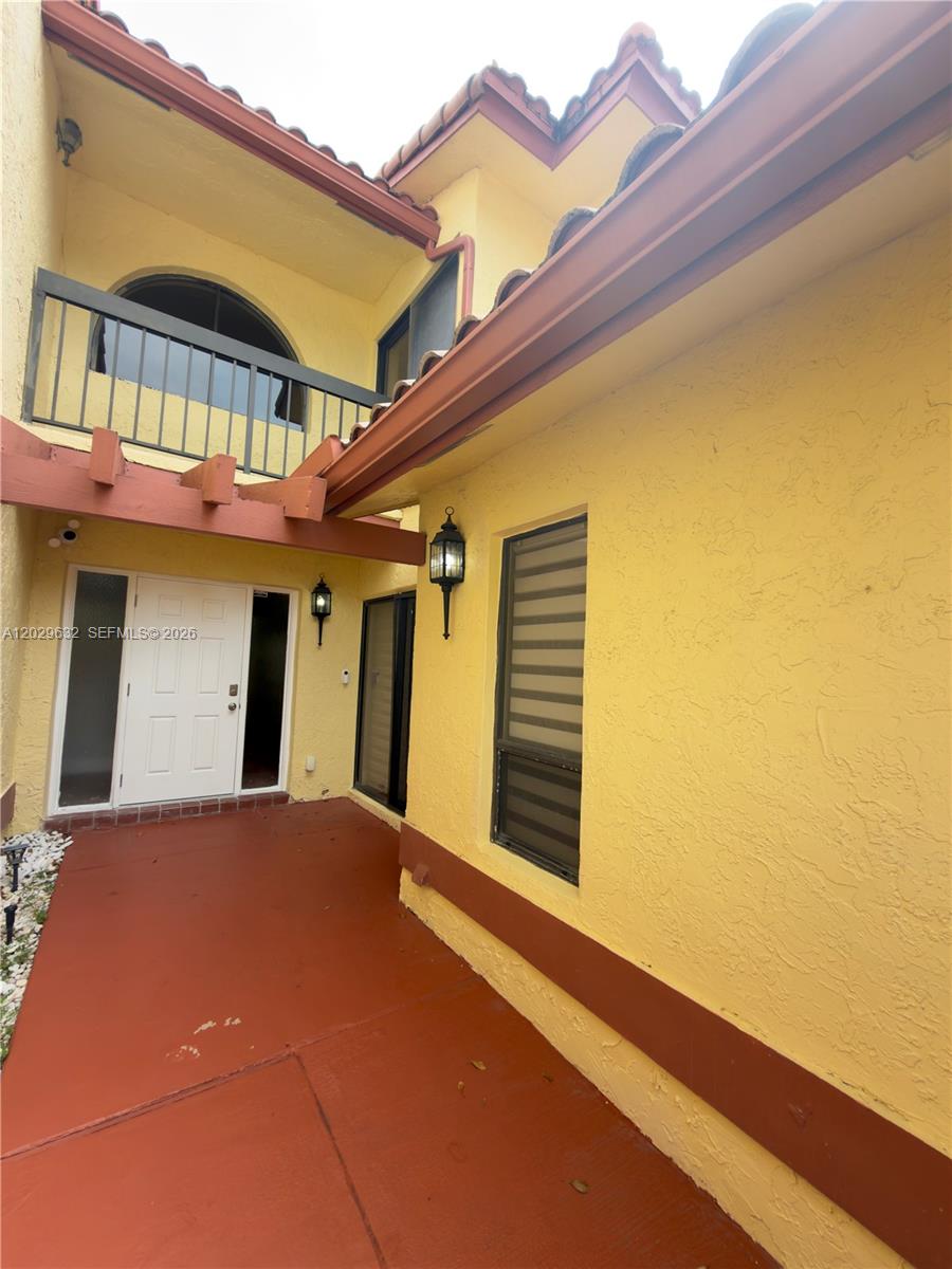 A yellow stucco house exterior features a red patio, white front door, and balcony — 5375 10th Fairway Dr # 2, Delray Beach FL 33484, DELRAY BEACH, FL