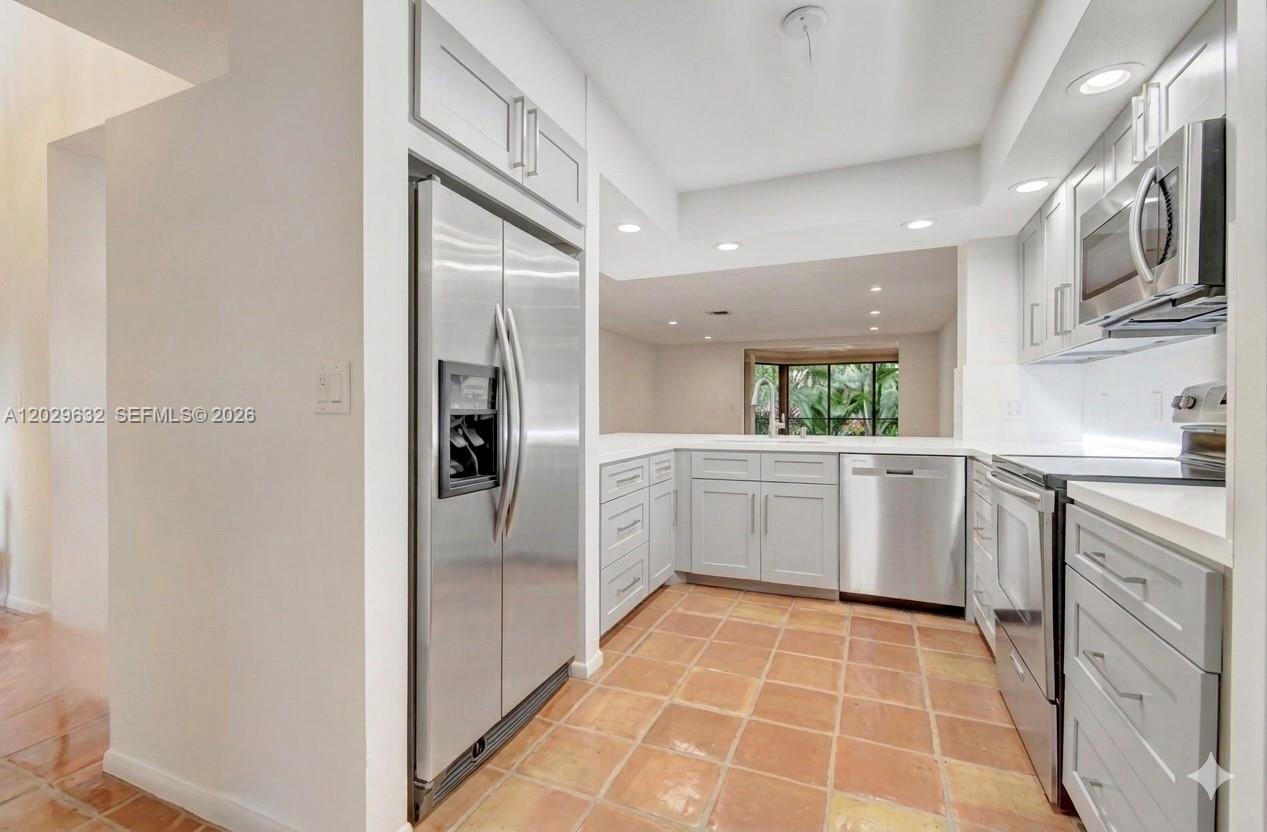 A kitchen features light gray cabinets, stainless steel appliances, and terracotta tile flooring — 5375 10th Fairway Dr # 2, Delray Beach FL 33484, DELRAY BEACH, FL