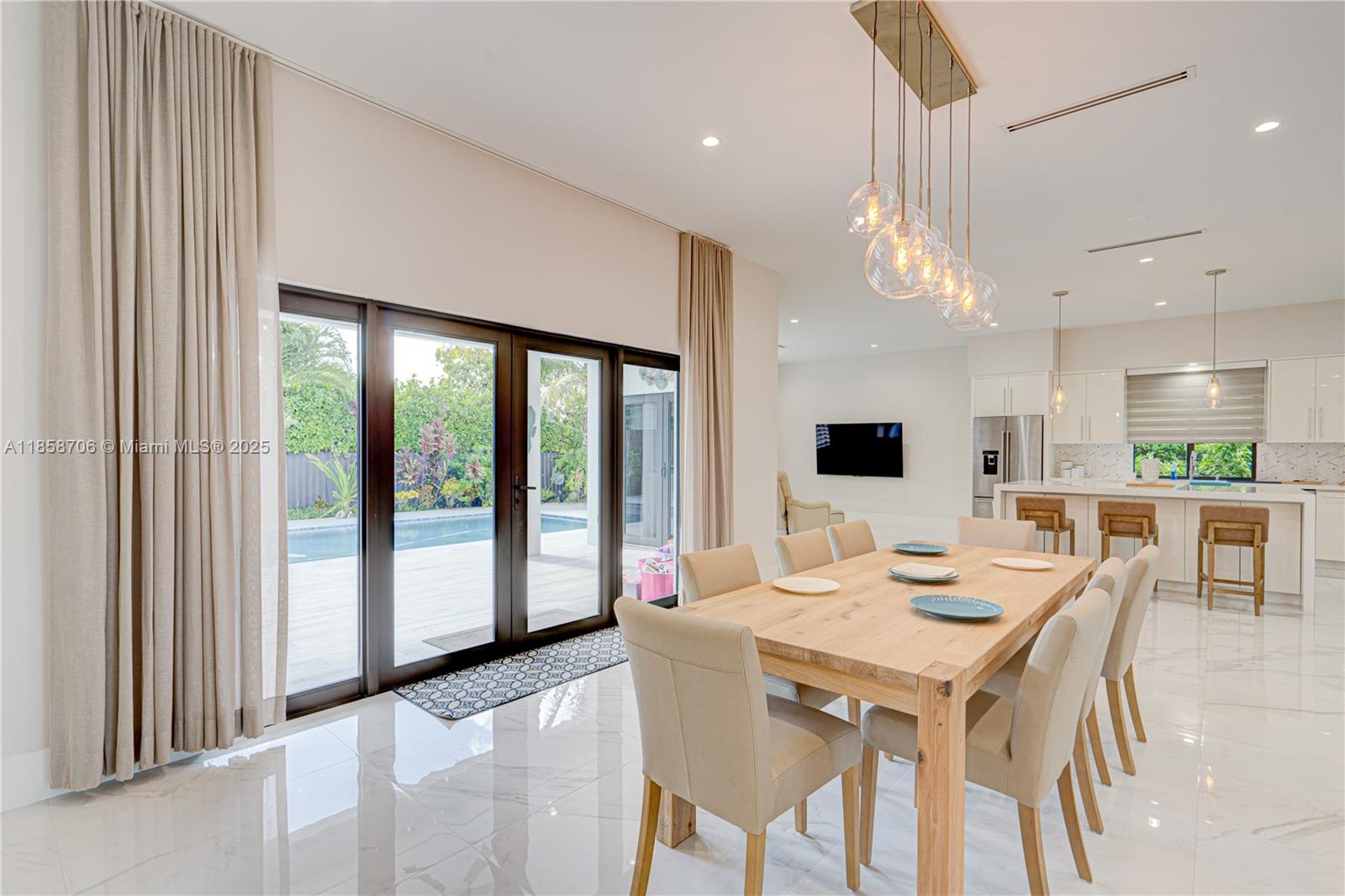 A dining area with a wooden table and chairs sits adjacent to a modern kitchen — 2521 SW 105th Ave, Miami FL 33165, MIAMI, FL