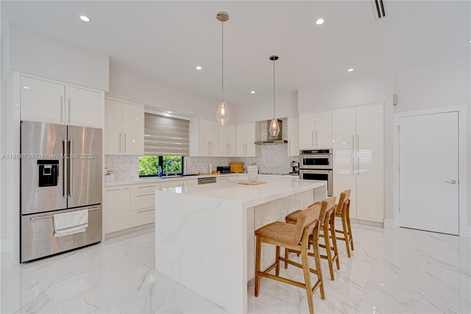 A modern white kitchen features a large marble-topped island, stainless steel appliances, and bar stools — 2521 SW 105th Ave, Miami FL 33165, MIAMI, FL