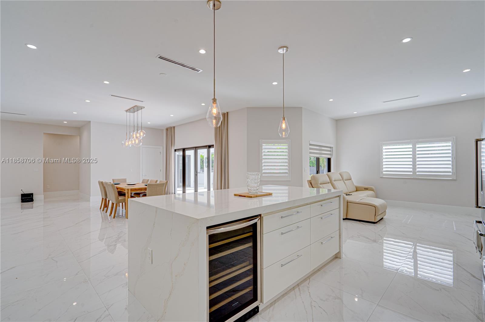 A modern kitchen island with a wine cooler sits in an open-concept living and dining area — 2521 SW 105th Ave, Miami FL 33165, MIAMI, FL