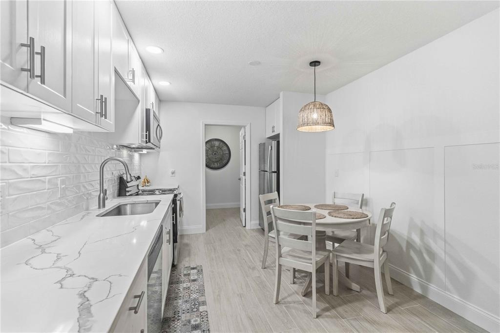 A white kitchen features marble countertops, stainless steel appliances, and a small dining area — 4237 66TH STREET CIRCLE W UNIT S-4237, BRADENTON, FL