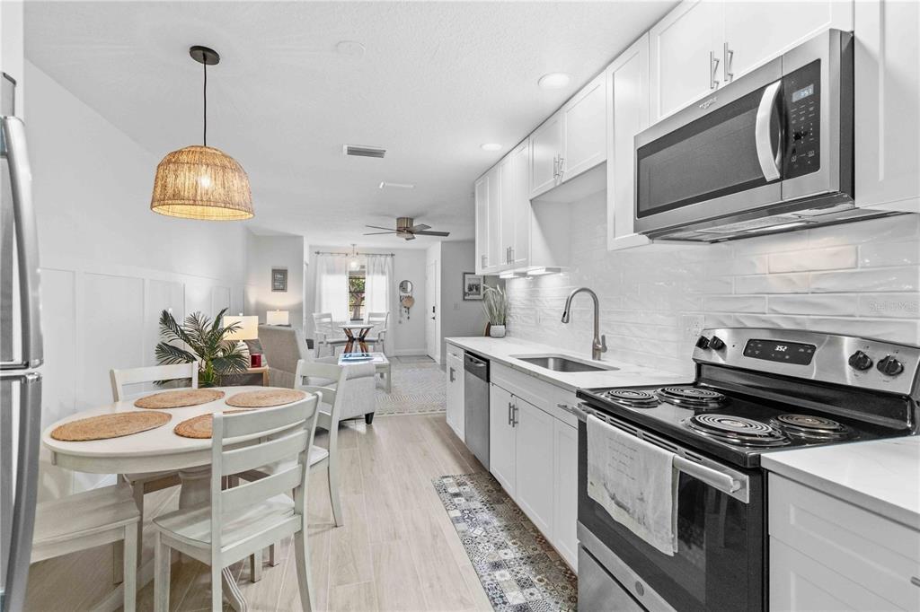 A white kitchen with stainless steel appliances opens into a dining area and living room — 4237 66TH STREET CIRCLE W UNIT S-4237, BRADENTON, FL