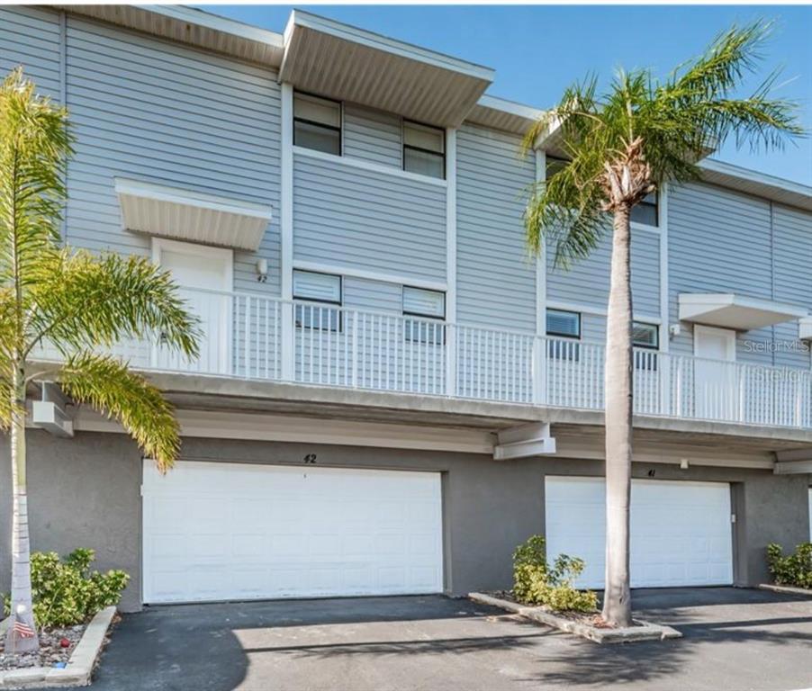 A two-story townhouse exterior with gray siding, a white balcony, and two ground-level garages — 19823 GULF BOULEVARD UNIT 42, INDIAN SHORES, FL