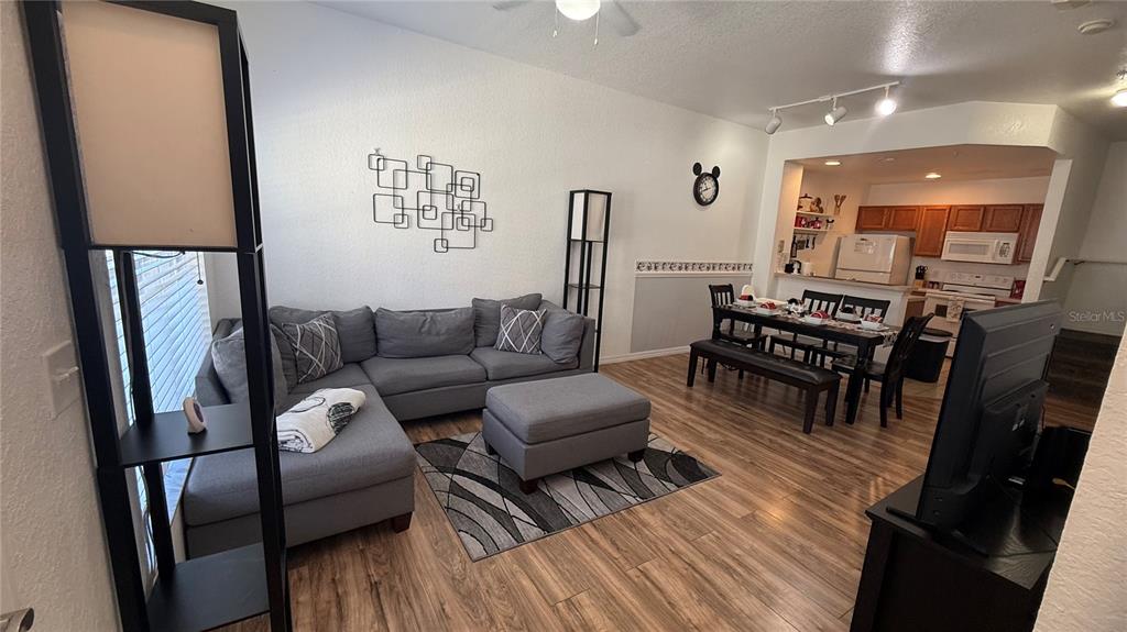 A living room with a gray sectional sofa and dining area with wood-look flooring — 4563 YELLOWGOLD ROAD E UNIT 106, KISSIMMEE, FL