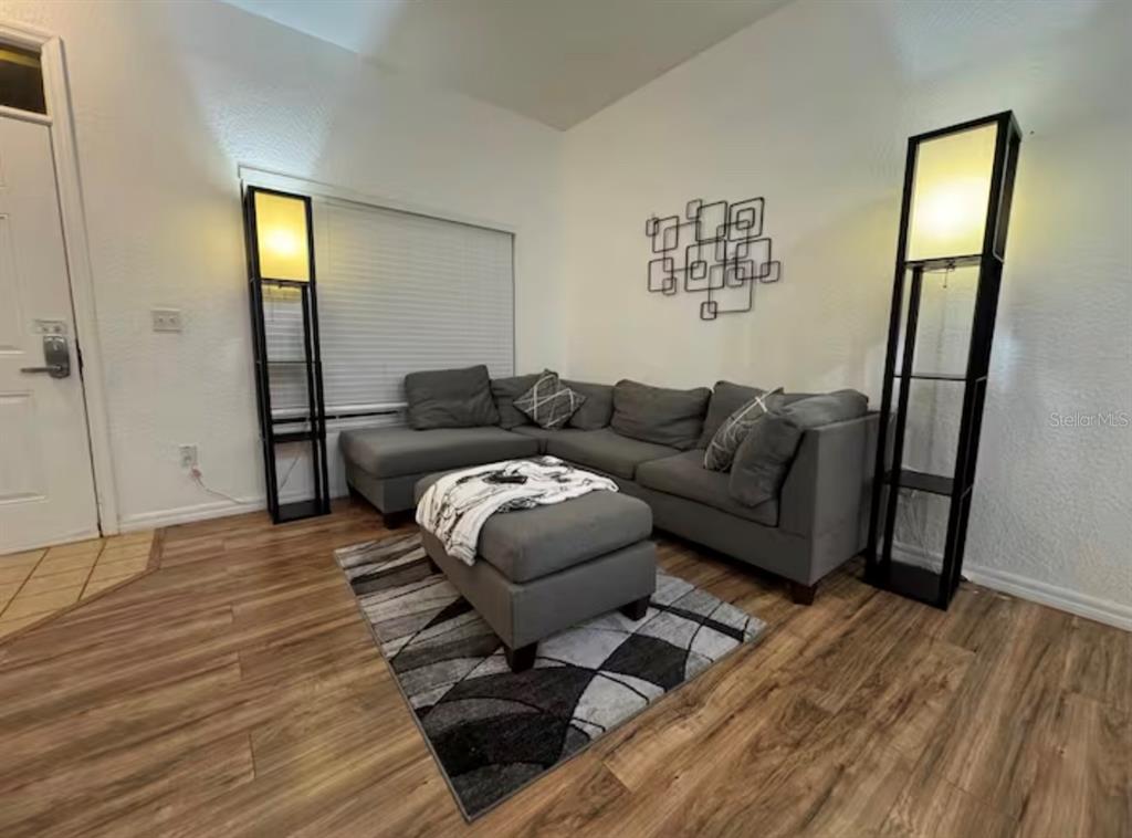 A living room features a gray sectional sofa, matching ottoman, area rug, and two floor lamps — 4563 YELLOWGOLD ROAD E UNIT 106, KISSIMMEE, FL