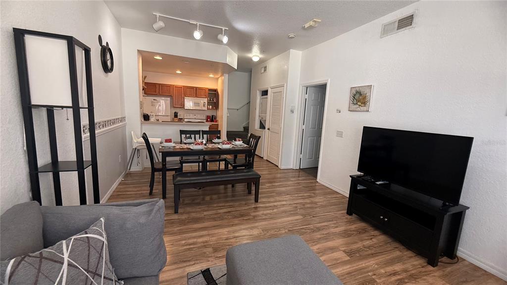 An open-concept living and dining area features wood-look flooring, white walls, and a kitchen — 4563 YELLOWGOLD ROAD E UNIT 106, KISSIMMEE, FL
