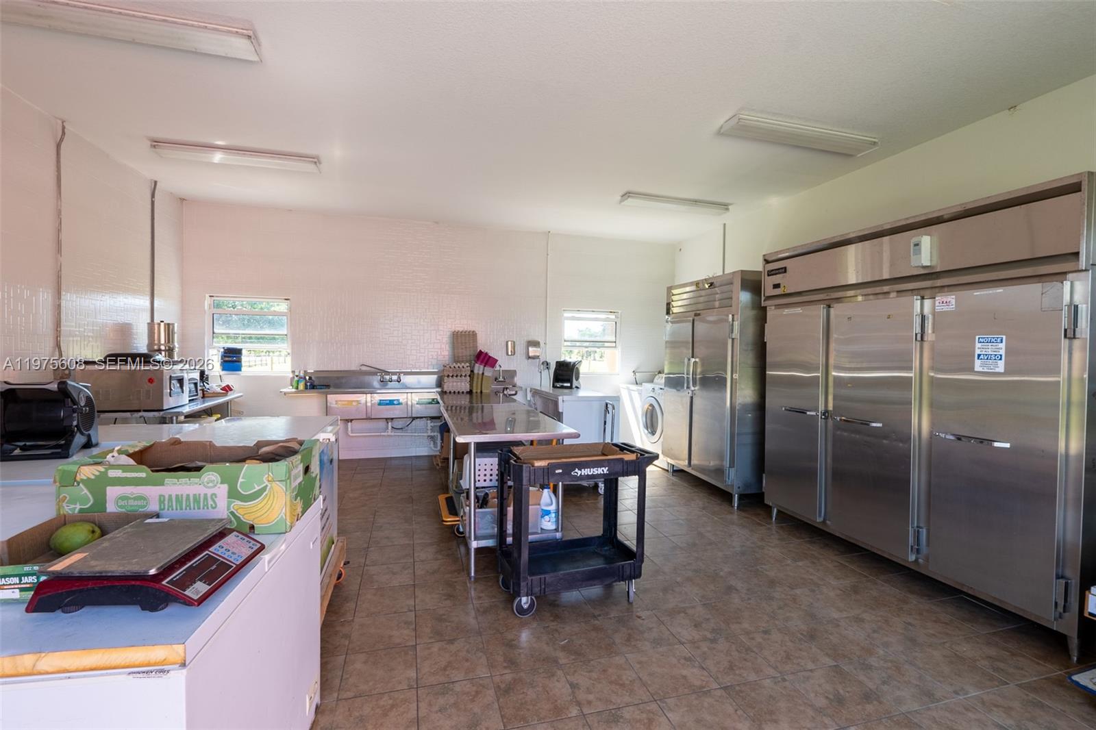 A commercial kitchen features stainless steel appliances, a sink, tile flooring, and white walls — 21810 NW 270TH ST, Okeechobee FL 34972, OKEECHOBEE, FL
