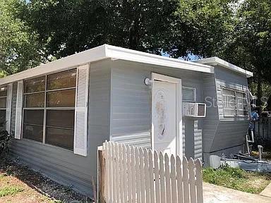A light gray mobile home exterior features white shutters, a white front door, and a fence — 3000 CLARCONA RD UNIT 401, APOPKA, FL