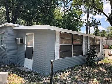 A gray mobile home exterior features white trim, a window air conditioner, and white shutters — 3000 CLARCONA RD UNIT 401, APOPKA, FL