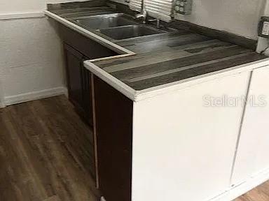 A kitchen features a double-basin sink, dark wood-look countertops, and white lower cabinets — 3000 CLARCONA RD UNIT 401, APOPKA, FL
