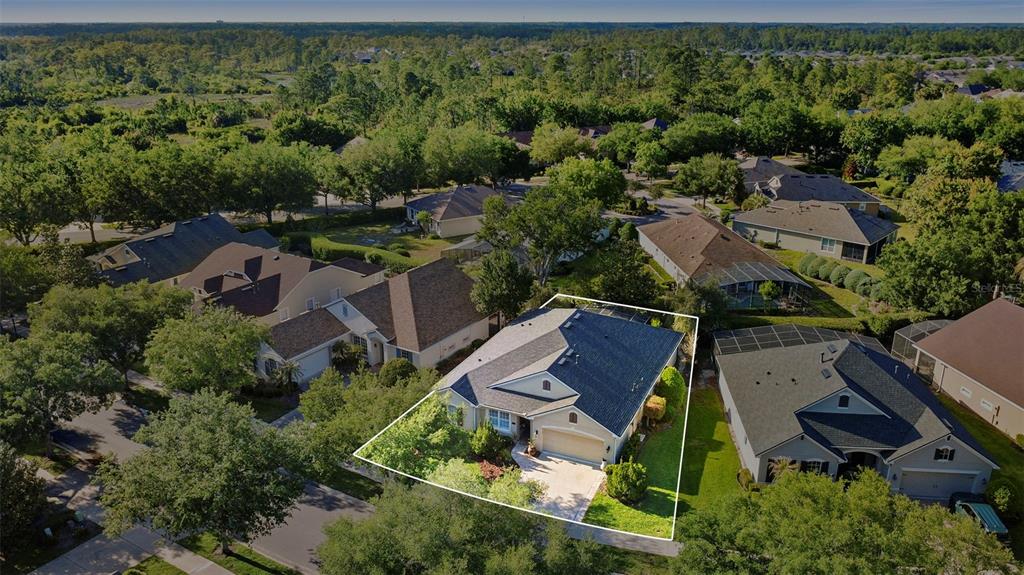 An aerial view shows a single-story house with a dark roof and a paved driveway — 1609 VICTORIA GARDENS DRIVE, DELAND, FL