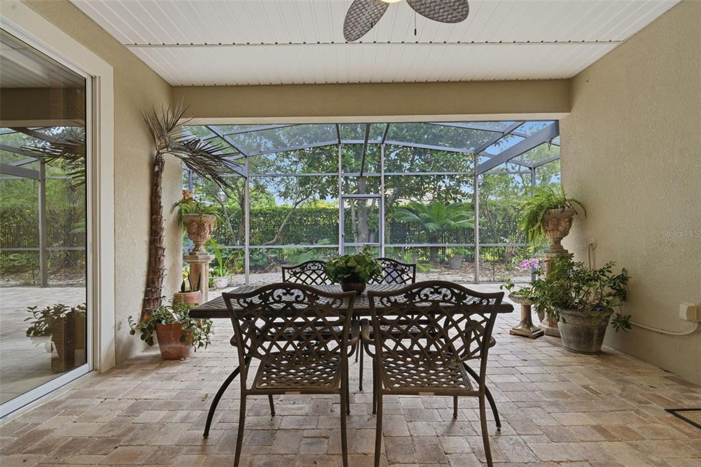 A covered patio features a dining set, potted plants, and a screened-in view of trees — 1609 VICTORIA GARDENS DRIVE, DELAND, FL