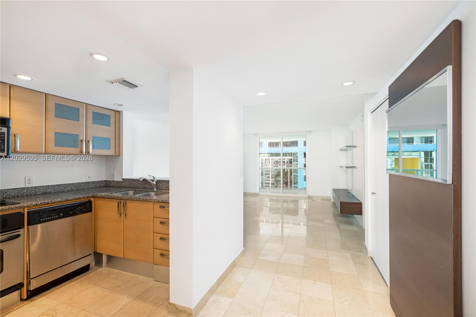 A kitchen with light wood cabinets and stainless steel appliances opens to a living area — 2101 Brickell Ave # 1103, Miami FL 33129, MIAMI, FL