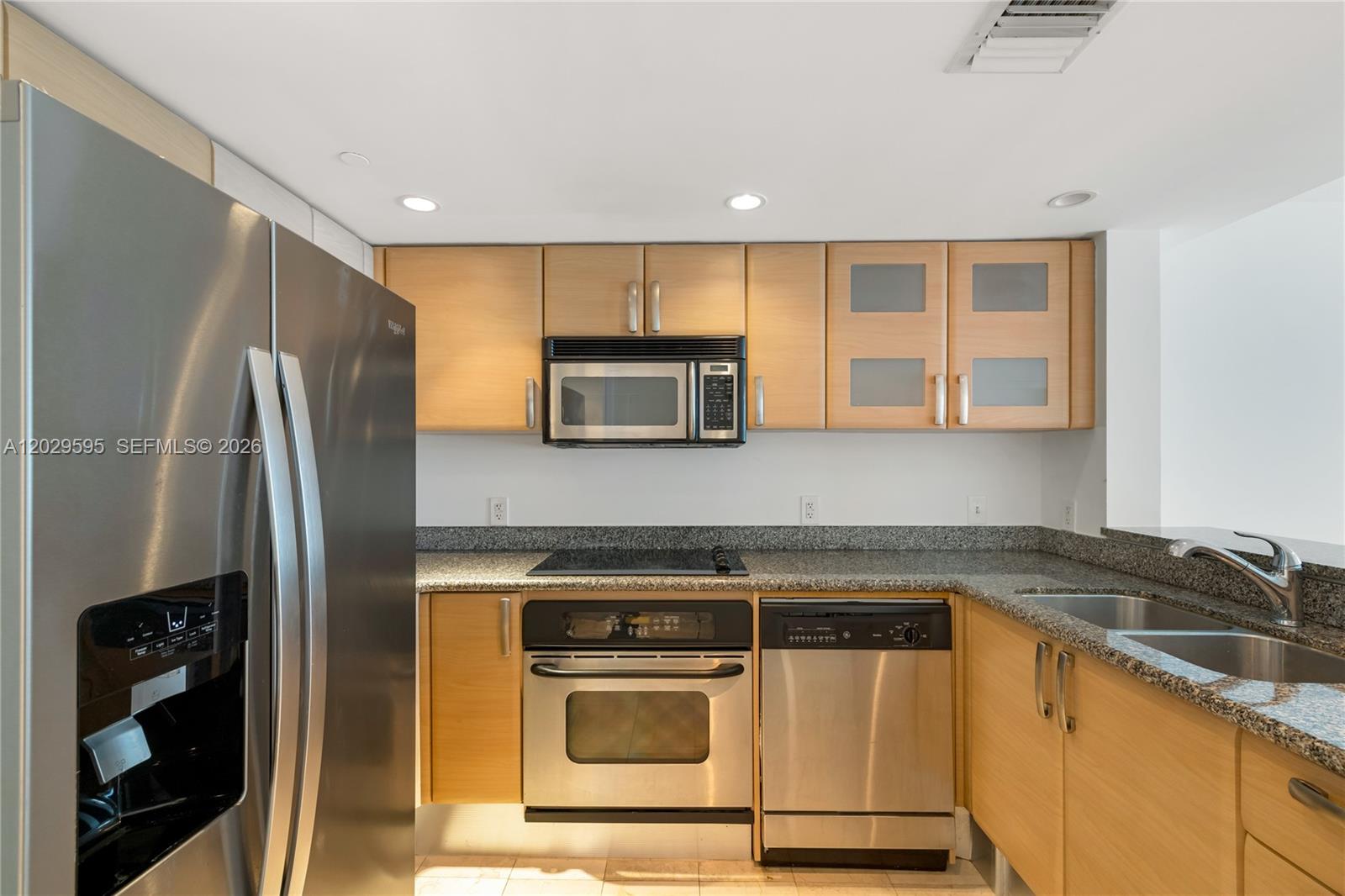 A kitchen features stainless steel appliances, light wood cabinets, and granite countertops — 2101 Brickell Ave # 1103, Miami FL 33129, MIAMI, FL