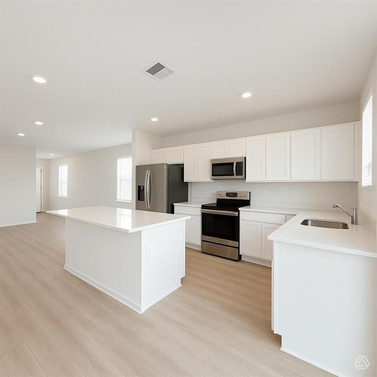 A modern kitchen features white cabinets, stainless steel appliances, and a central island — 13008 SASSAFRAS TRAIL, PARRISH, FL
