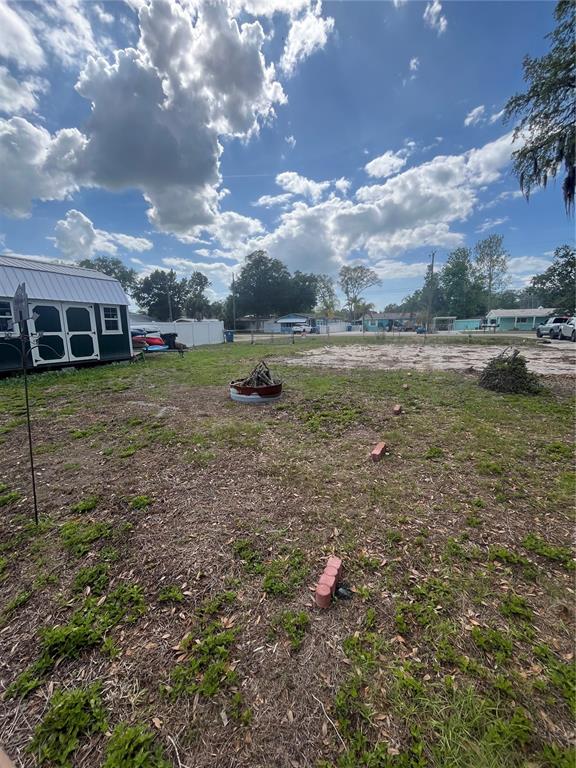 A backyard features a shed, a fire pit, and scattered bricks on a grassy lot — 7206 BETHESDA COURT, WEEKI WACHEE, FL