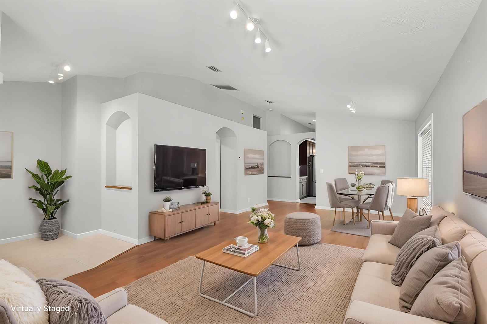 This virtually staged living and dining area features vaulted ceilings, wood floors, and arched niches — 1959 NW Marsh Rabbit Lane, Jensen Beach FL 34957, JENSEN BEACH, FL