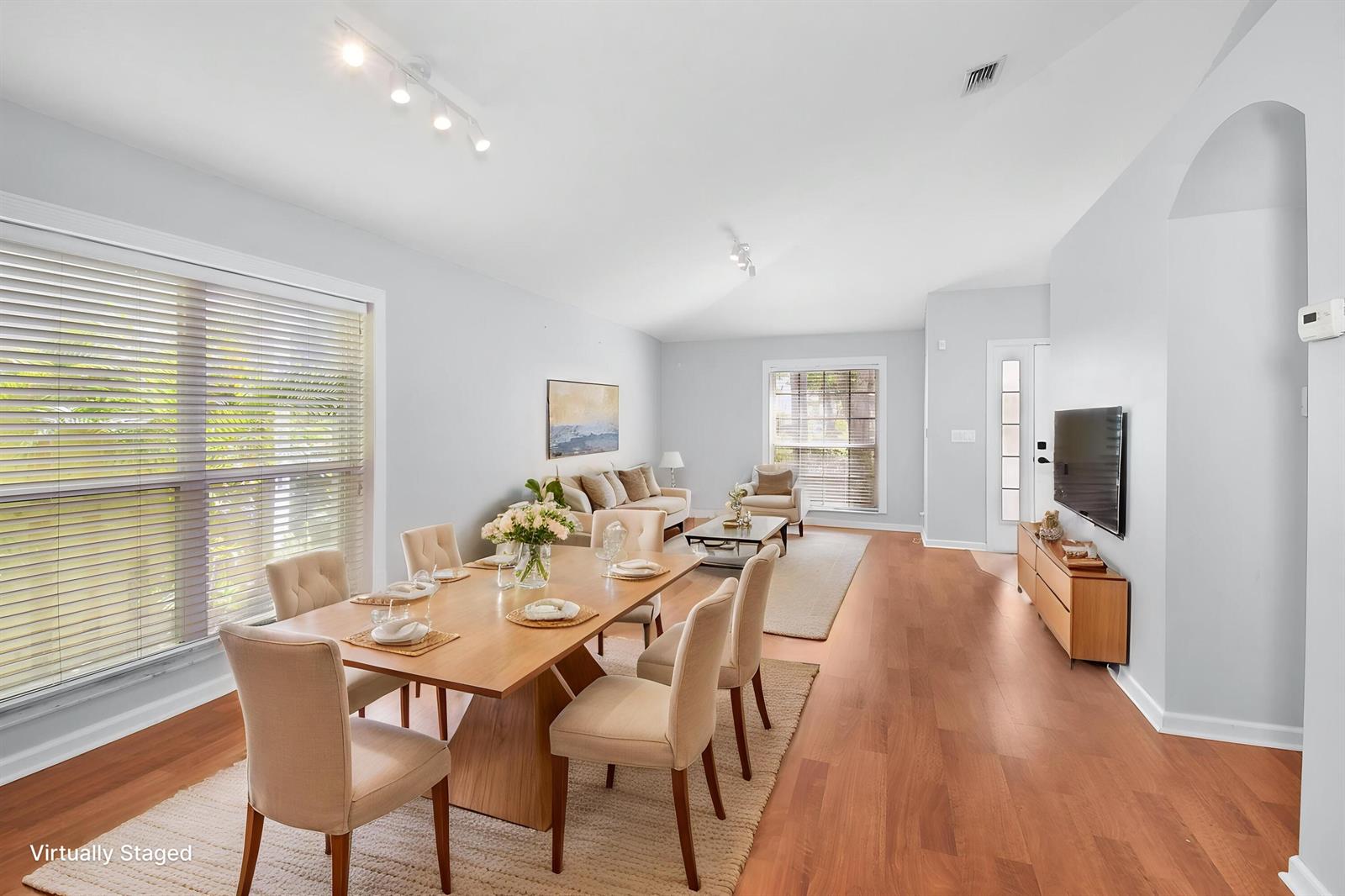 A dining and living area with hardwood floors, neutral walls, and large windows — 1959 NW Marsh Rabbit Lane, Jensen Beach FL 34957, JENSEN BEACH, FL