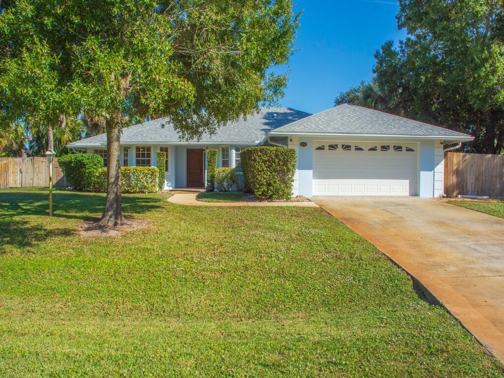 A single-story house with a light blue exterior, a two-car garage, and a large front lawn — 6130 60th Court, Vero Beach FL 32967, VERO BEACH, FL