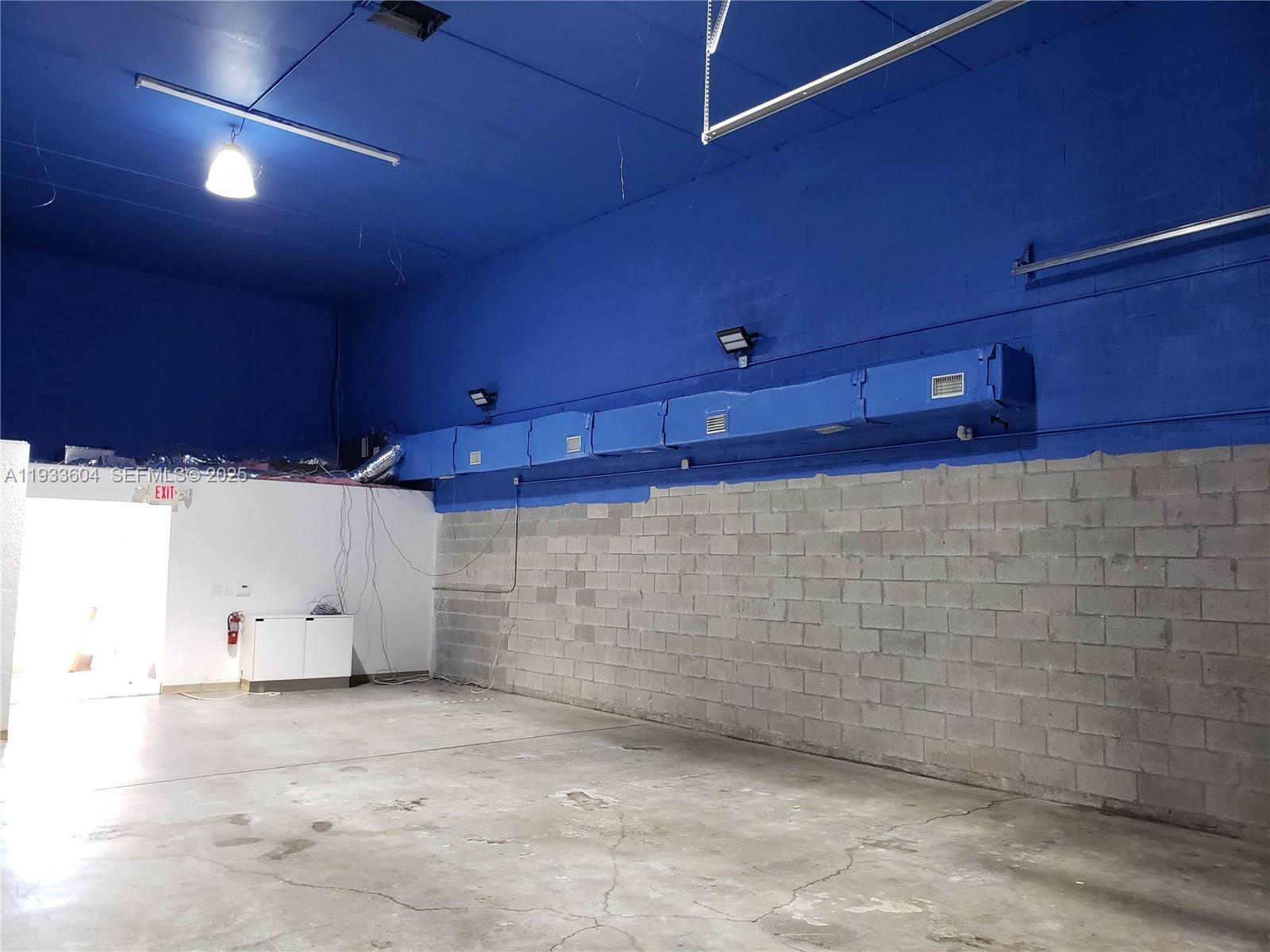 An industrial space features a blue ceiling, exposed concrete block walls, and overhead ductwork — 13491 NW 47th Ave # 2, Opa-Locka FL 33054, OPA-LOCKA, FL