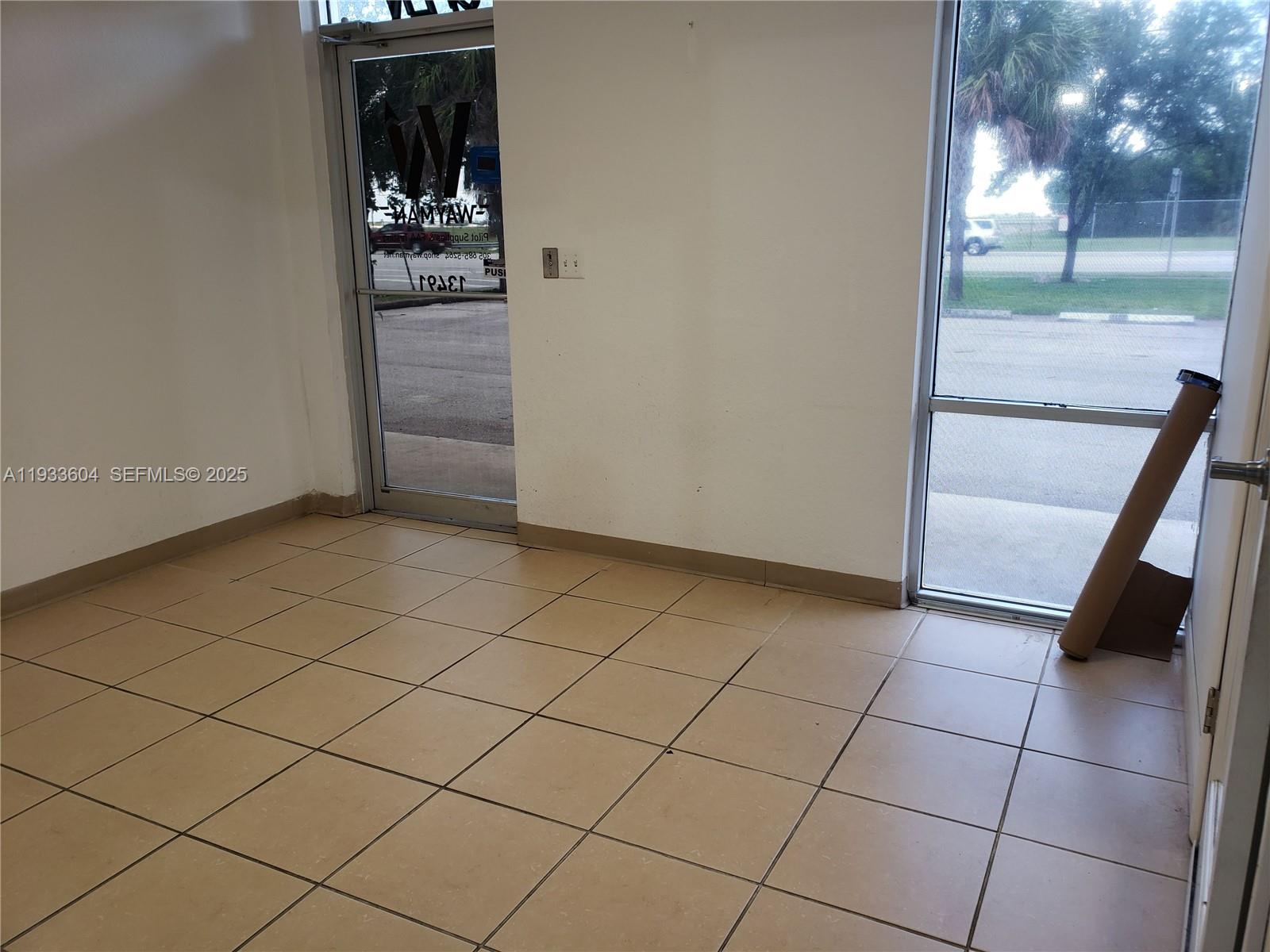 An interior view of a commercial space with beige tile flooring and glass entry doors — 13491 NW 47th Ave # 2, Opa-Locka FL 33054, OPA-LOCKA, FL